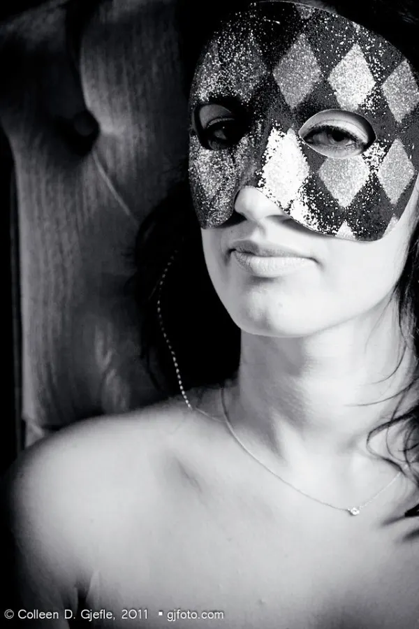 Black and white image of woman wearing harlequin mask